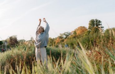 Senior woman enjoying stretching exercises in a lush green park.